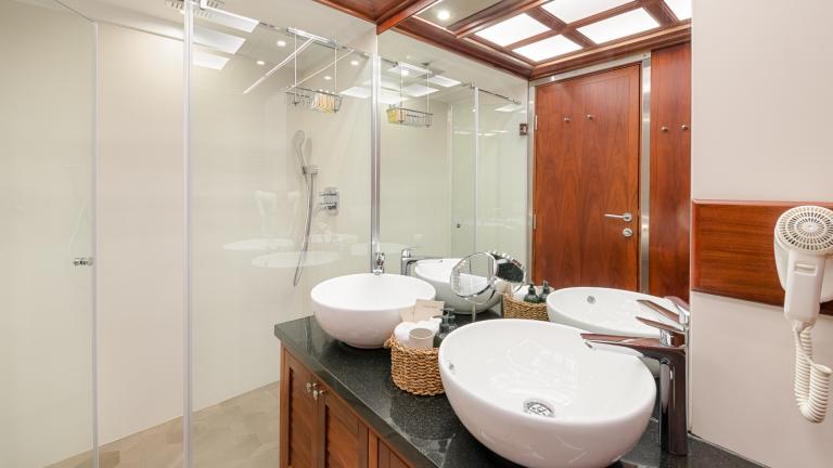 Ein helles Badezimmer mit ebenerdiger XXL Dusche, großem Spiegel und Doppel Waschbecken.